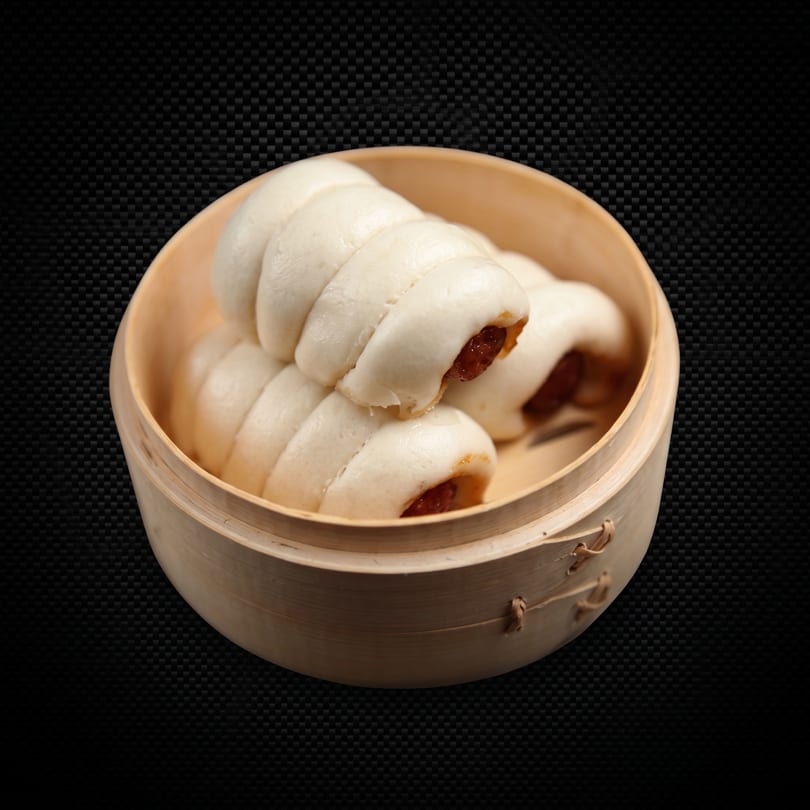 Steamed buns with a sweet filling, served in a traditional bamboo steamer.