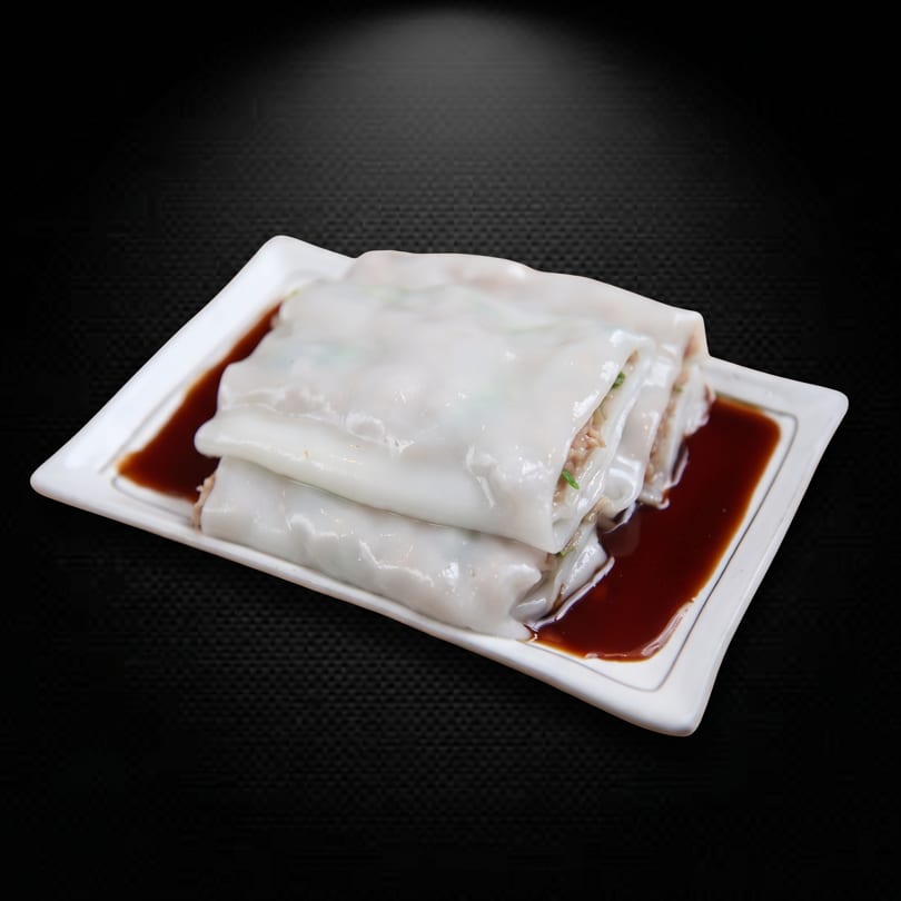 Chee cheong fun, rice noodle rolls with filling, served on a white plate with soy sauce.